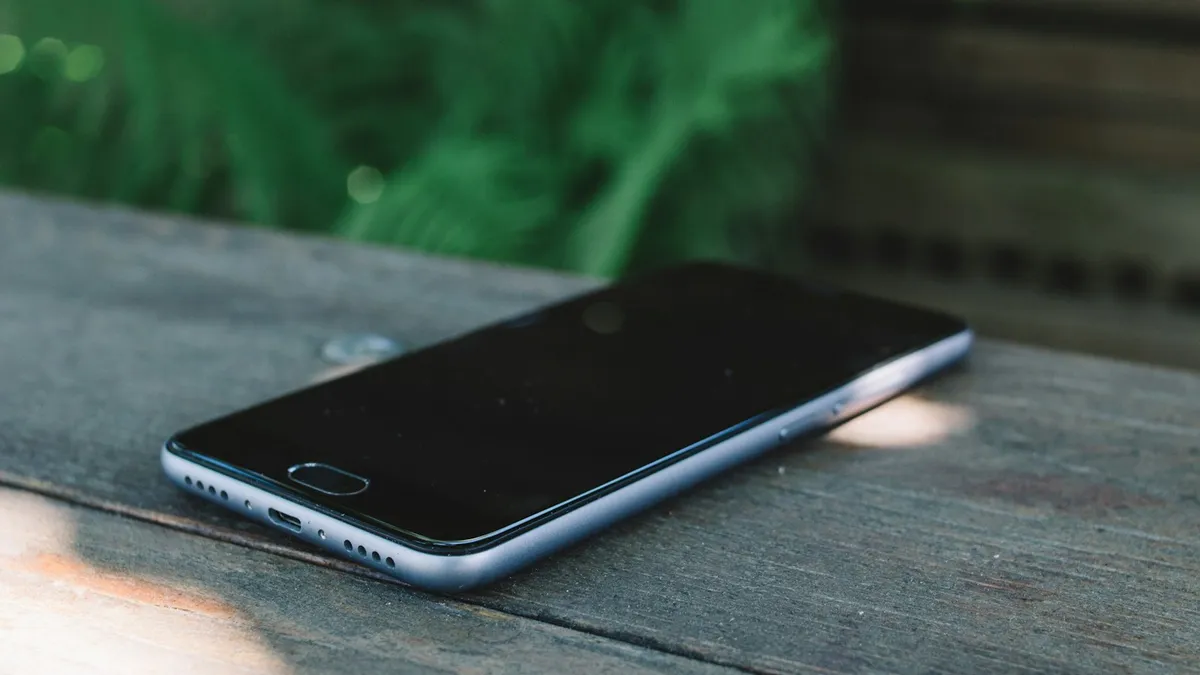 A phone turned off, resting face-down on a wooden table